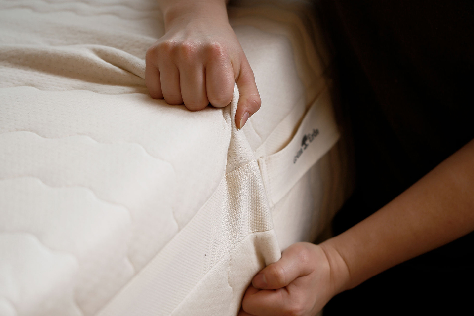 Mitarbeiterin die den Bezug über eine Matratze zieht