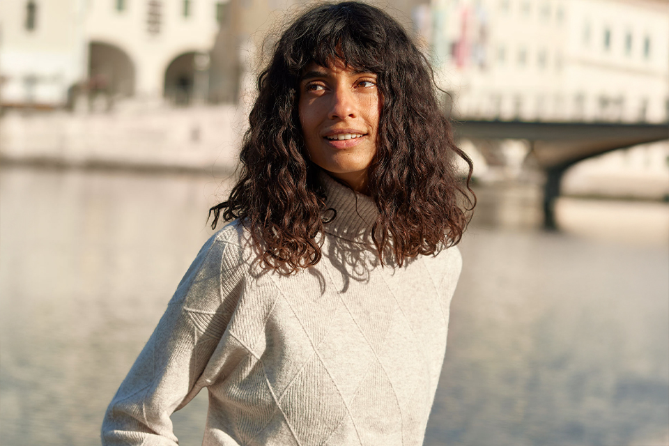 Frau am Flussufer in entspannter Pose mit natürlicher Kleidung