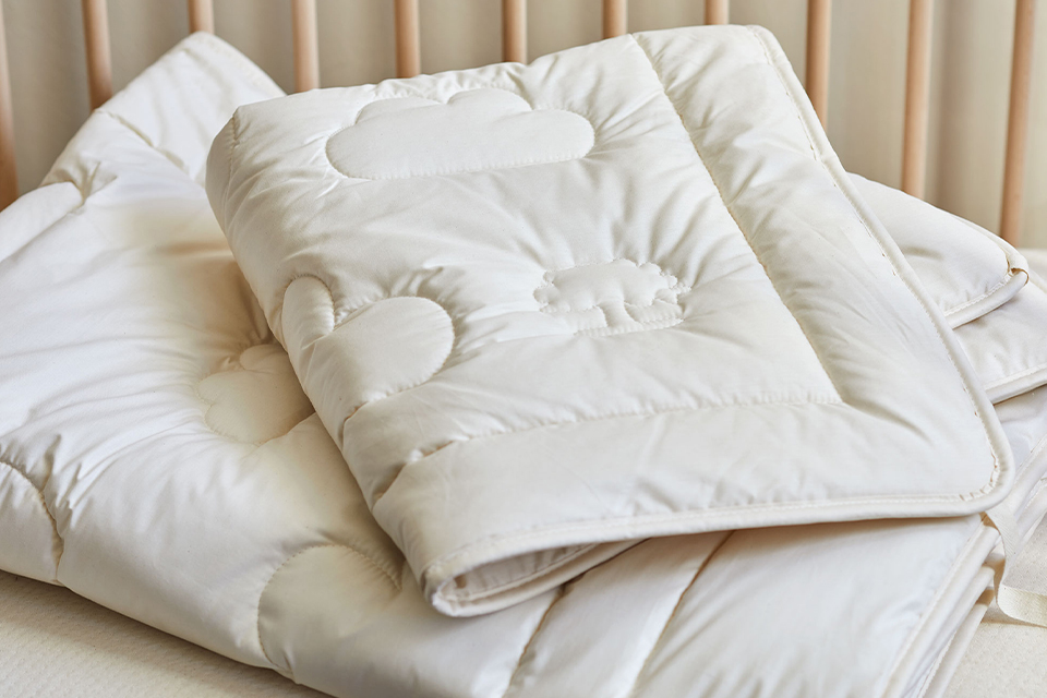 Zwei Bettdecken aufeinander gestapelt in einem Bett