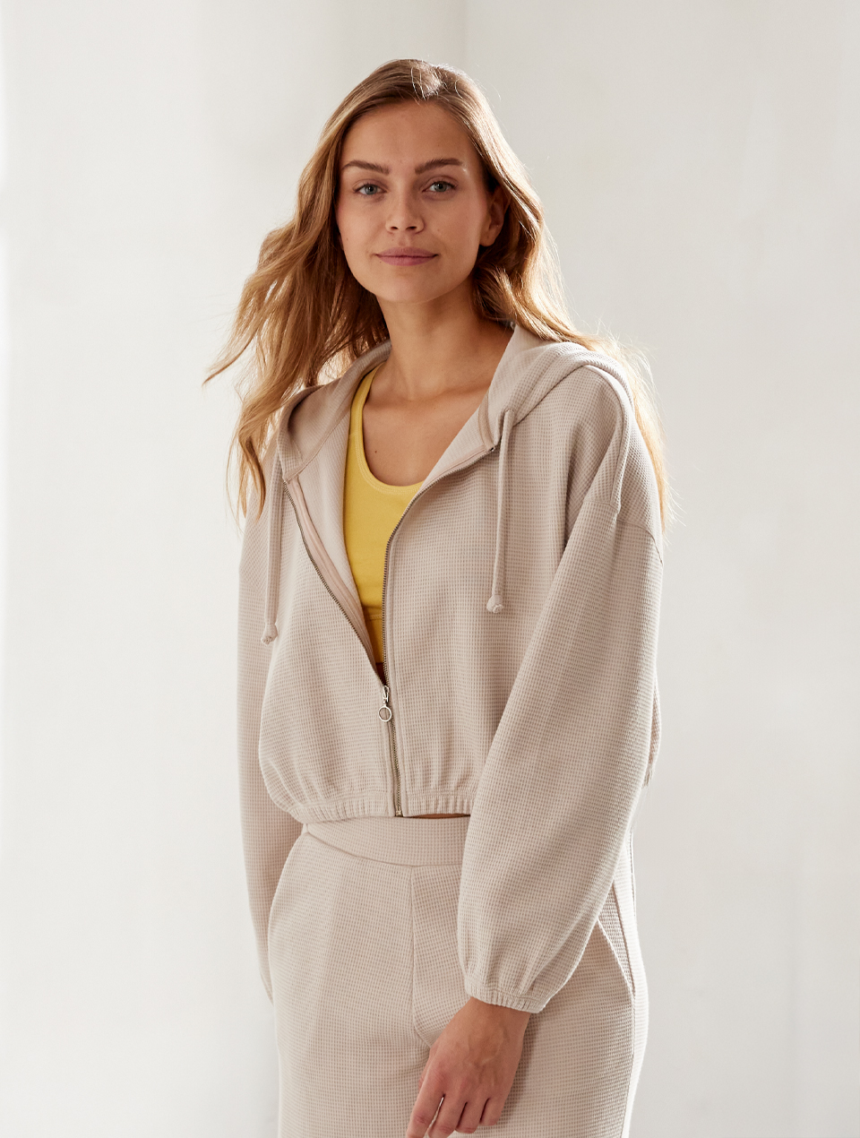 Frau im beigen Loungewear Set mit Waffelstruktur und gelbem Top