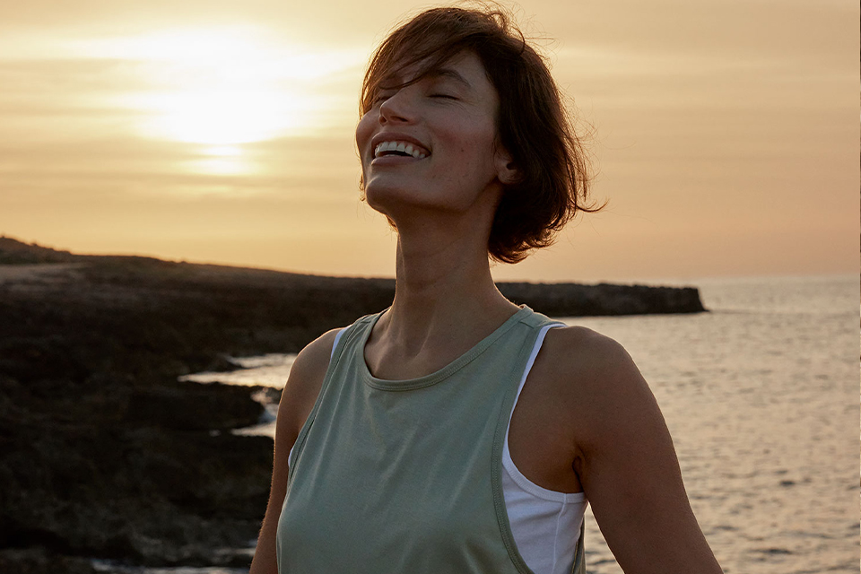 Frau lächelt am Strand im warmen Licht des Sonnenuntergangs