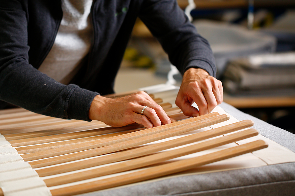 Hände richten sorgfältig Holzleisten auf Arbeitstisch aus