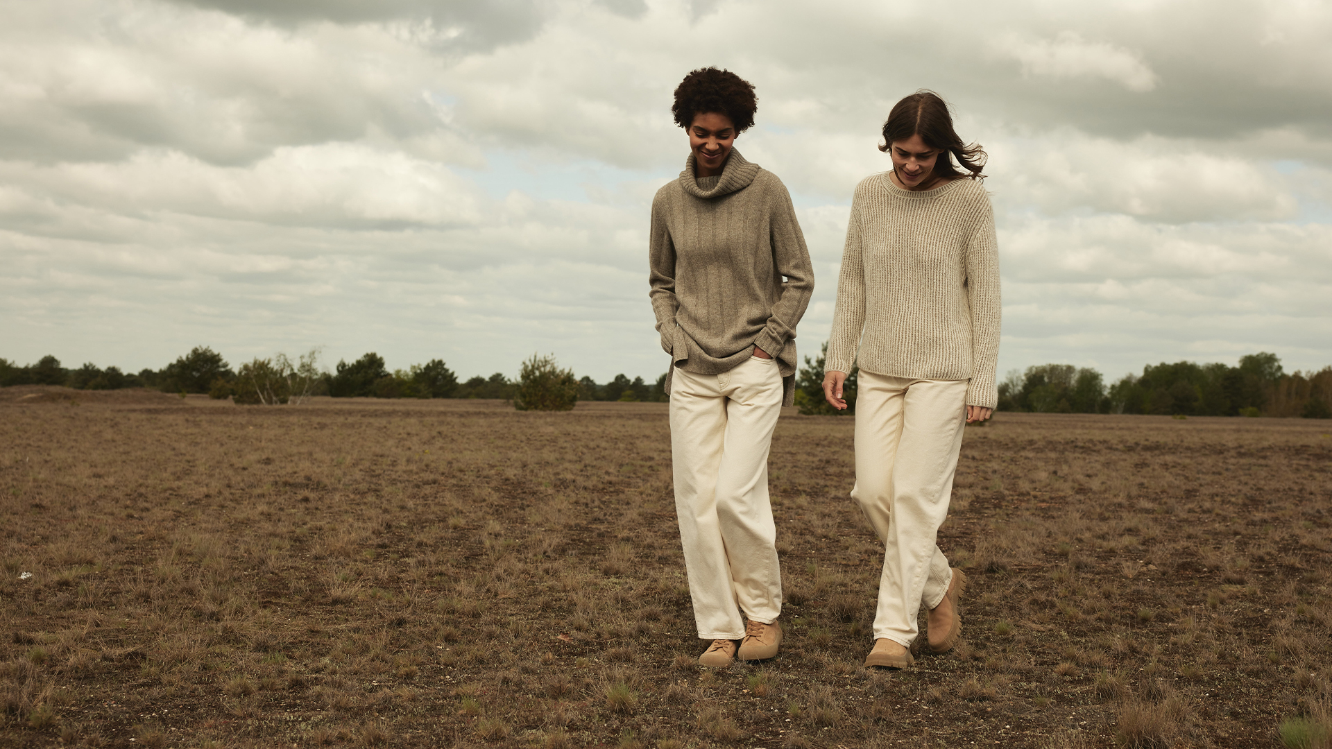 Zwei Personen gehen durch ein Feld in heller natürlicher Kleidung