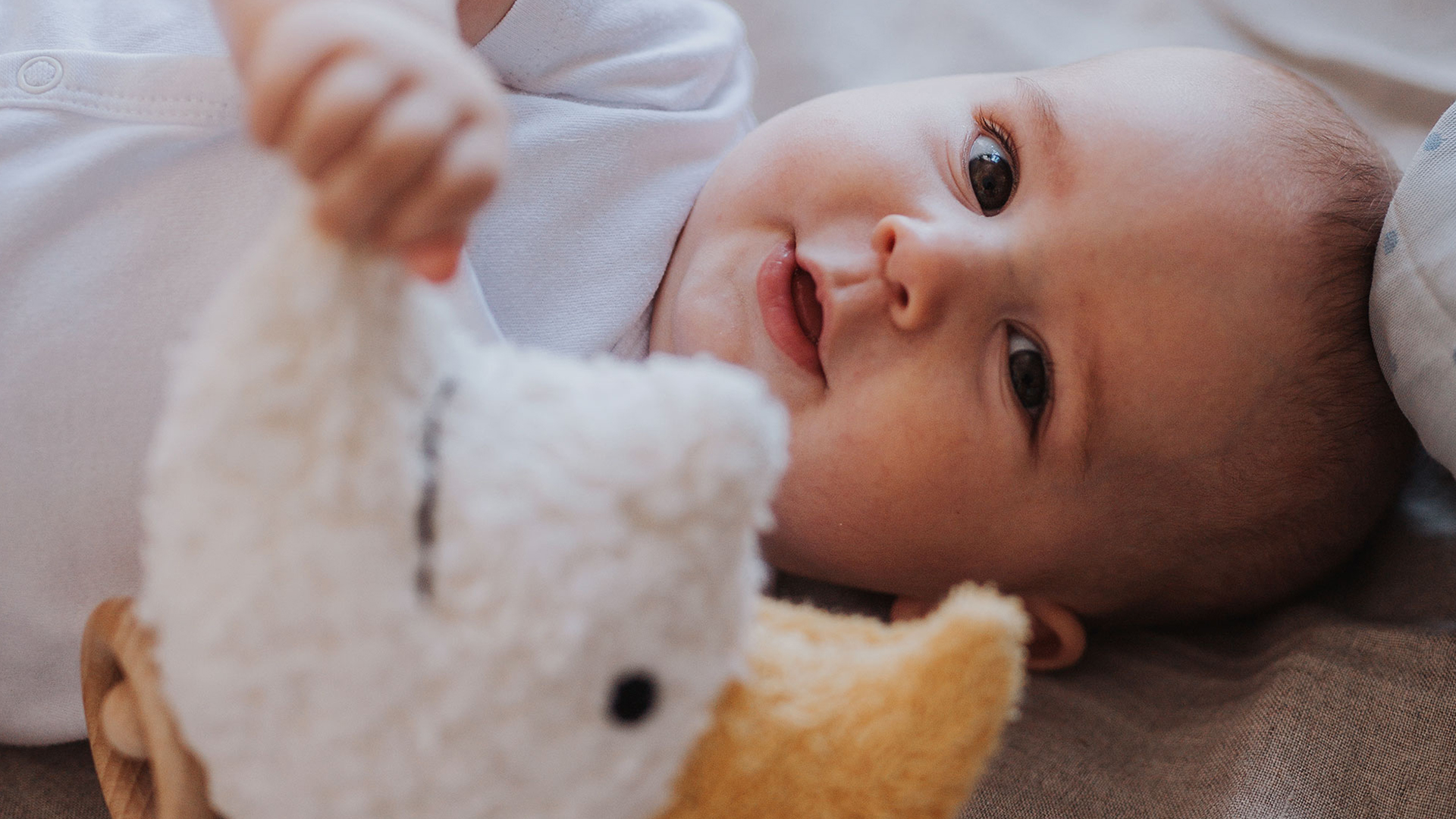 Lächelndes Baby spielt mit Spieluhr Mond