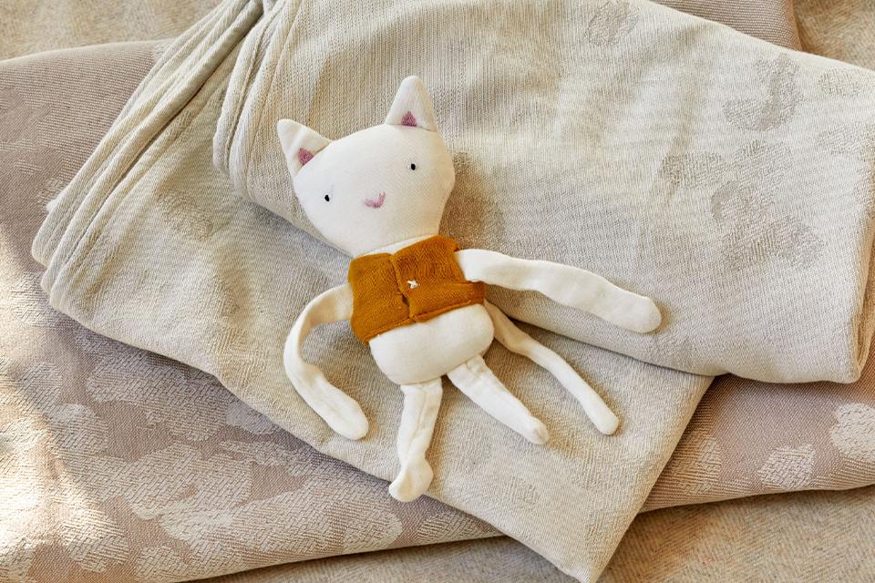 Kleines Kuscheltier liegt auf Babytragetüchern