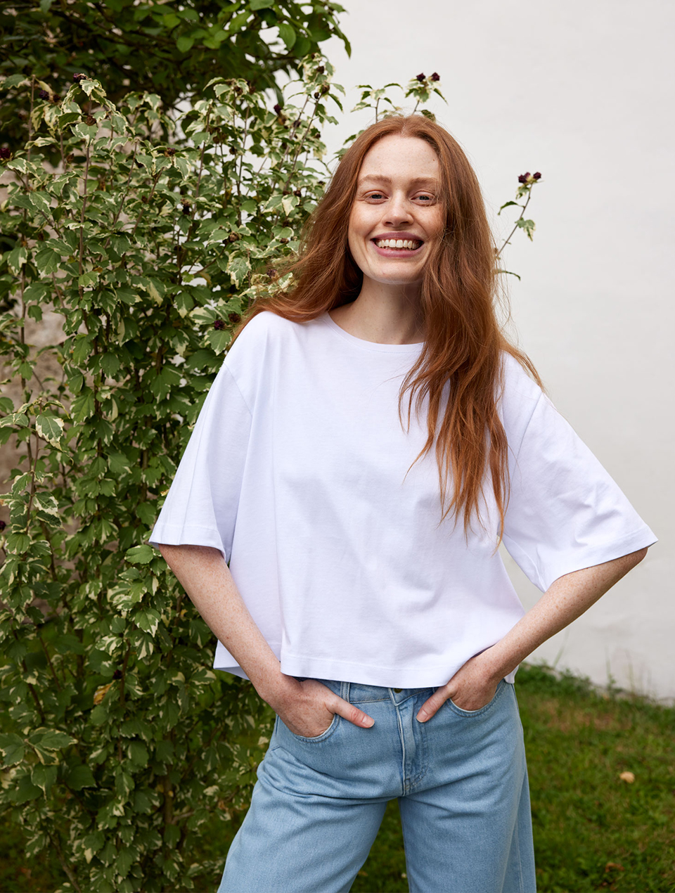 Frau trägt weißes Shirt und hellblaue Jeans in natürlicher Umgebung