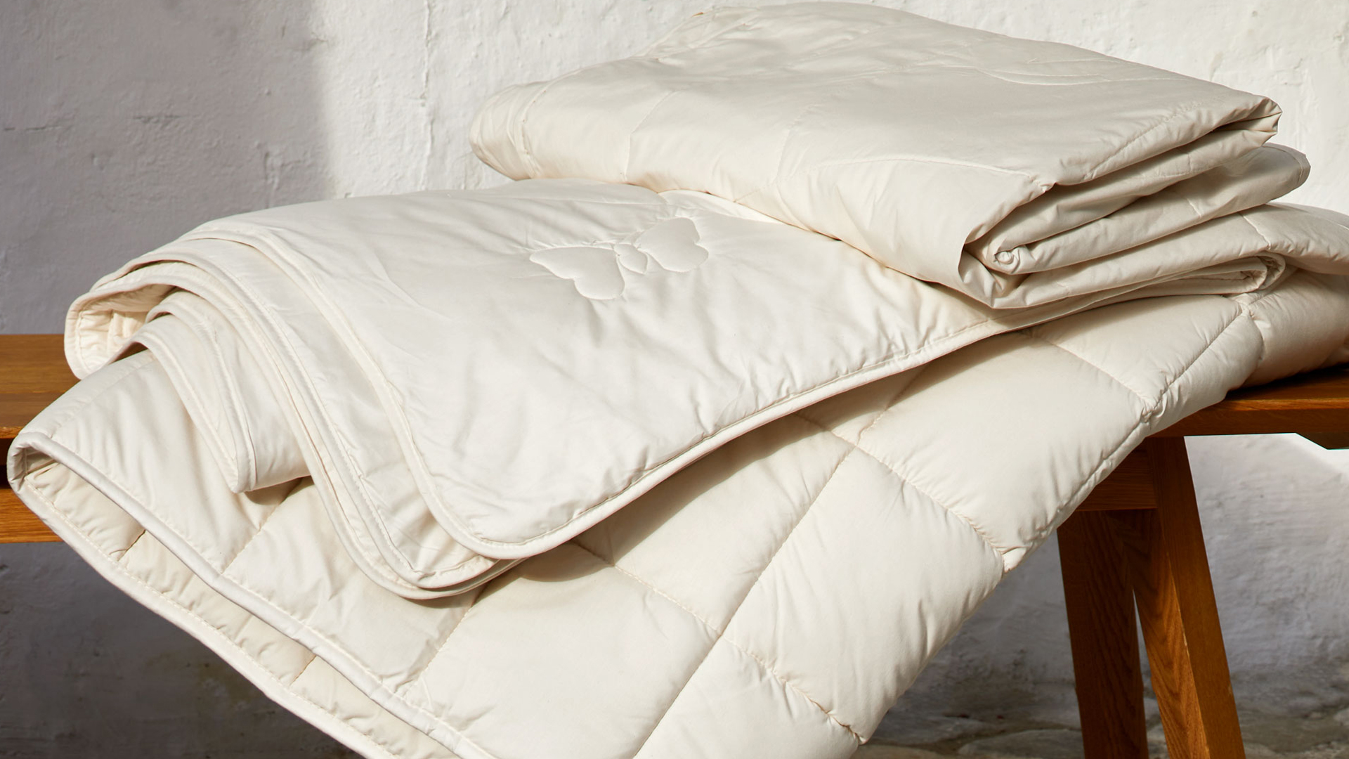Bettdecken gestapelt auf einer dekorativen Holzbank