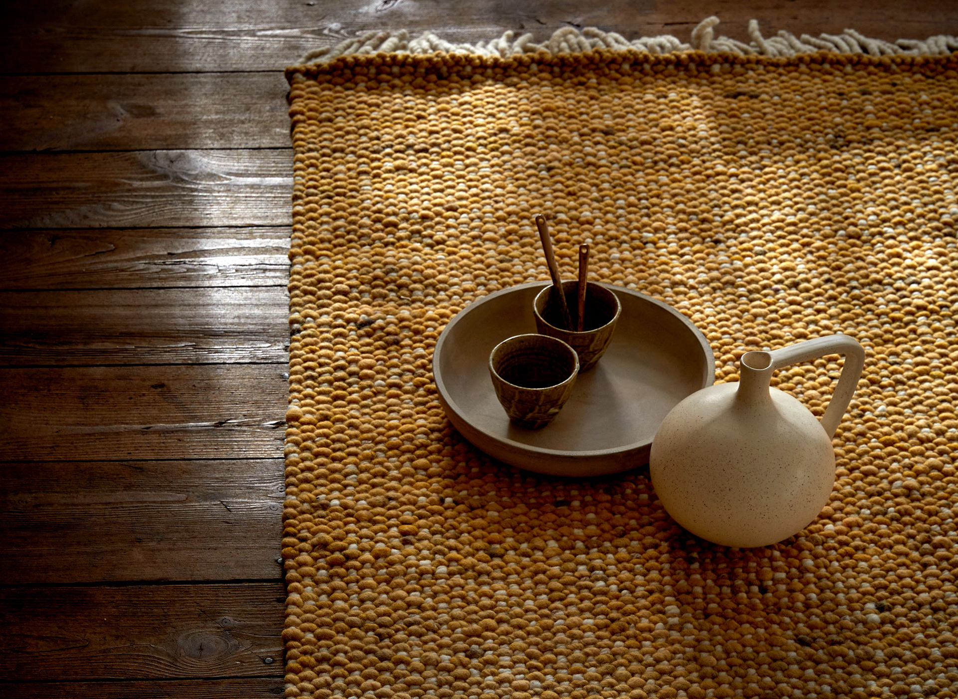 sandfarbener Teppich auf dem Boden liegend mit einer Vase und einer Schale mit Räucherstäbchen