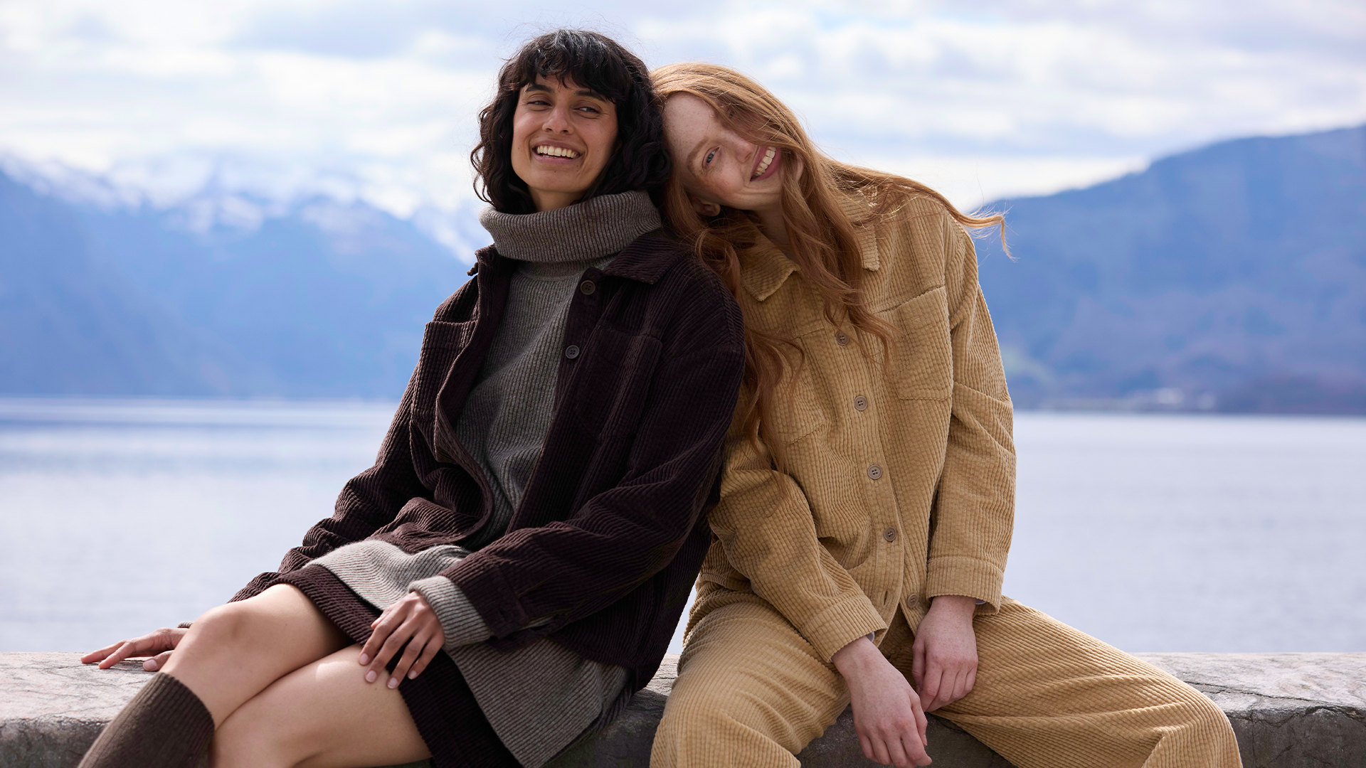 Zwei Frauen sitzen am See und genießen die Aussicht