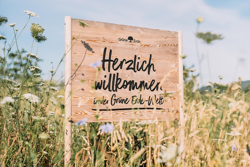 Schild in Wiese mit Aufschrift Herzlich willkommen im Grünen