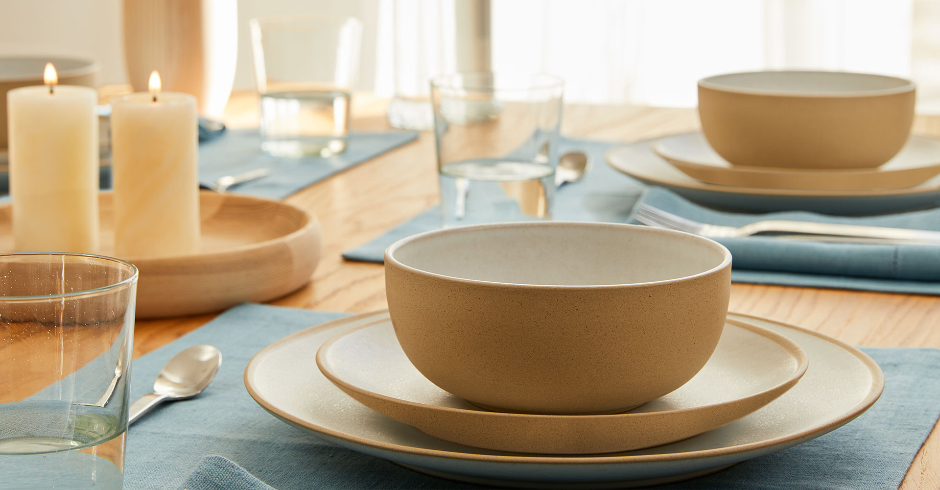 Dekorierter Tisch mit Gläser. Teller, Besteck und Kerzen in der Mitte