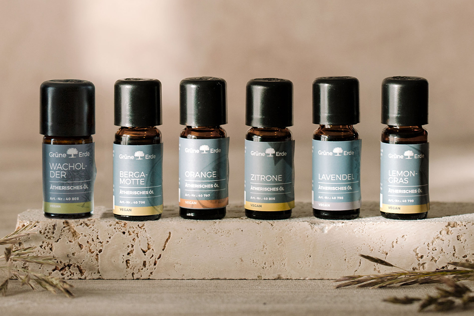 Sechs verschiedenfarbige Aromaöle nebeneinander auf einem Stein