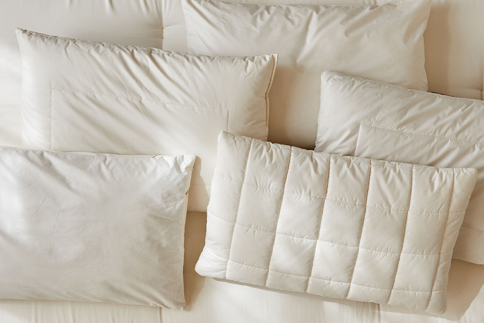 Fünf verschiedene ökologische Kopfkissen auf einer Naturmatratze