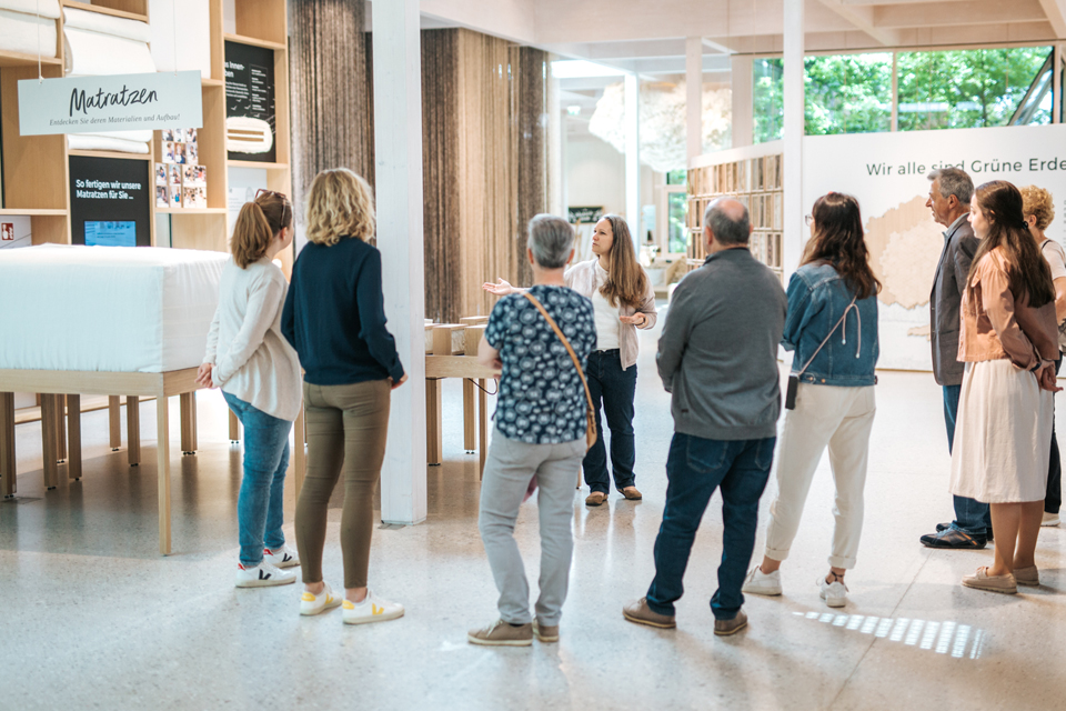 Besuchergruppe steht in hellem Foyer und hört aufmerksam zu