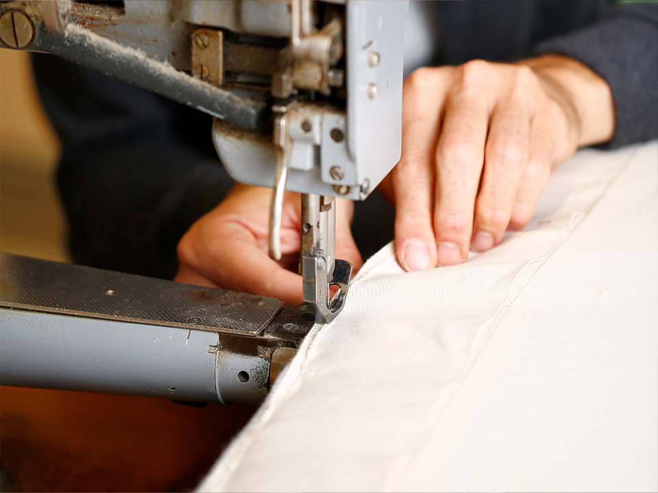 Näherin mit Nähmaschine beim fertigen eines Sofas