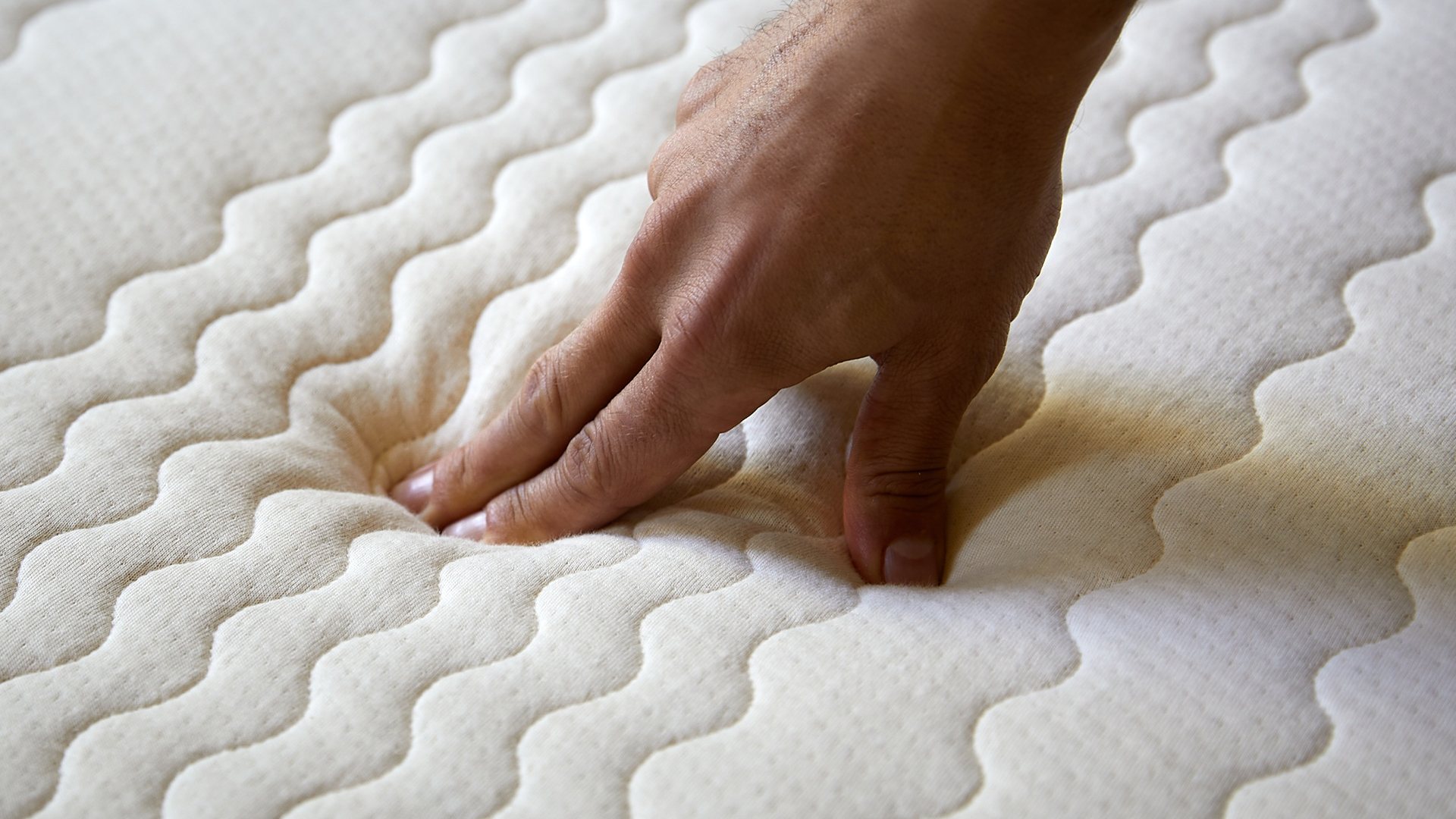 Hand drückt auf Matratze