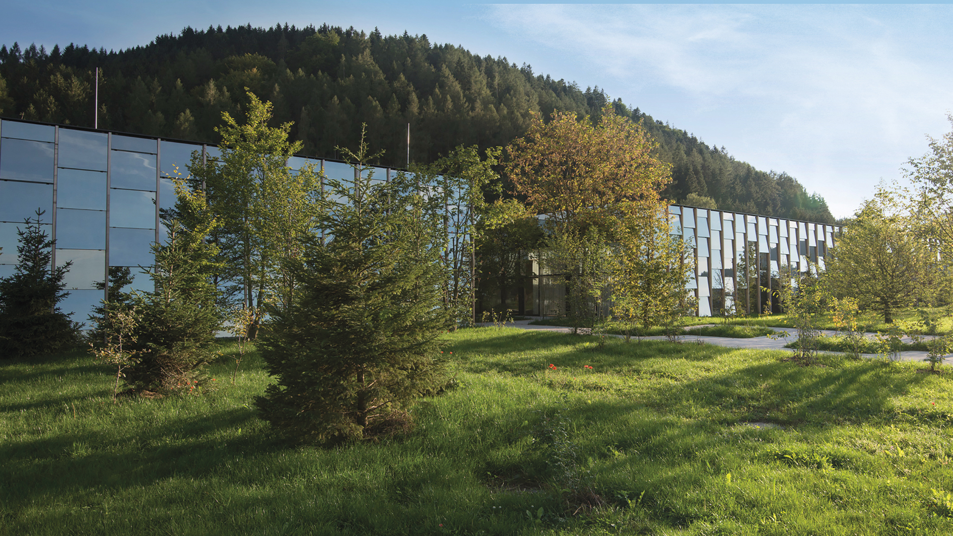 Modernes Gebäude in grüner Landschaft bei sonnigem Wetter