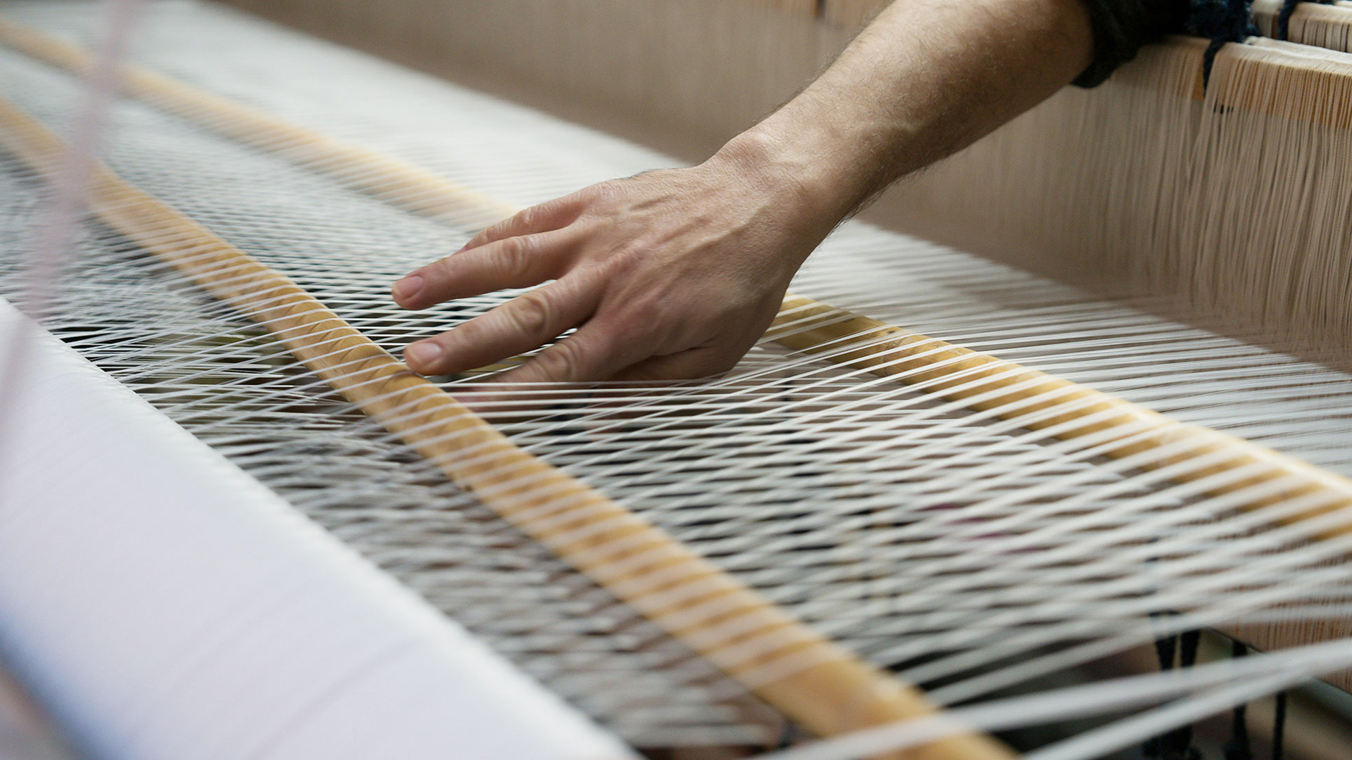 Detailbild von Hand, die einen Webstuhl betätigt