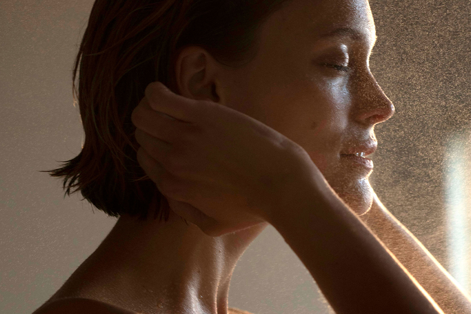 Frau schaut mit geschlossenen Augen in die Sonne