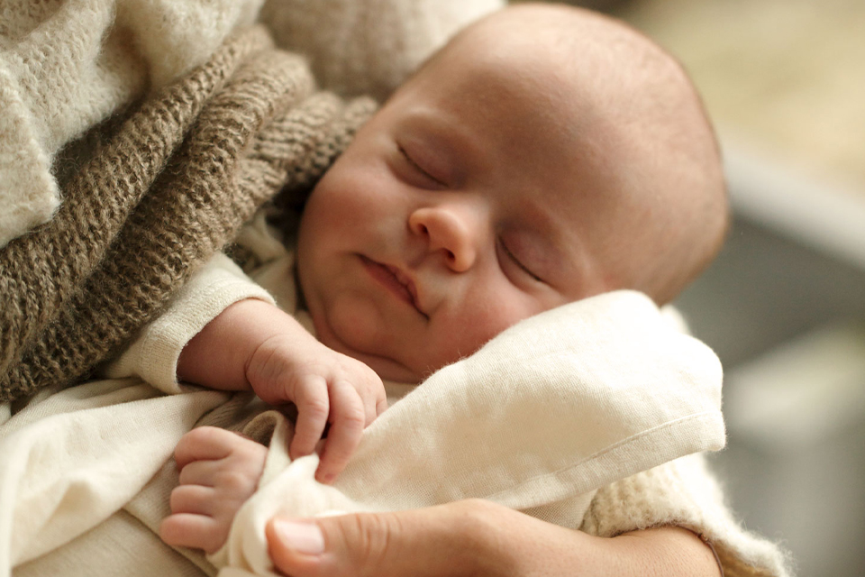 Ein schlafendes Baby in den Armen seiner Mutter