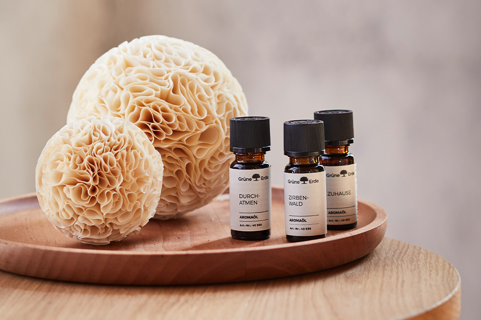 Auf einem Tablett liegende zwei Duftkugeln. Daneben stehen 3 Ätherische Öle
