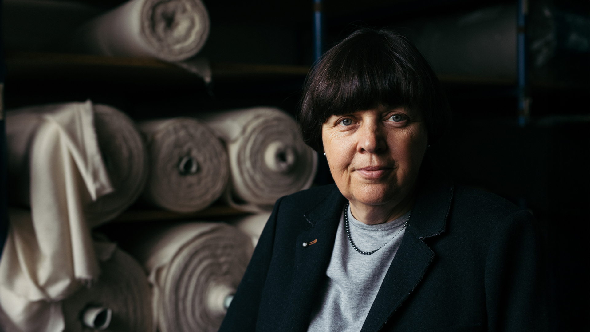 Lächelnde Frau steht vor Stoffrollen