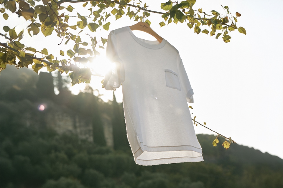 Weißes T Shirt hängt draußen im Sonnenlicht zwischen Bäumen