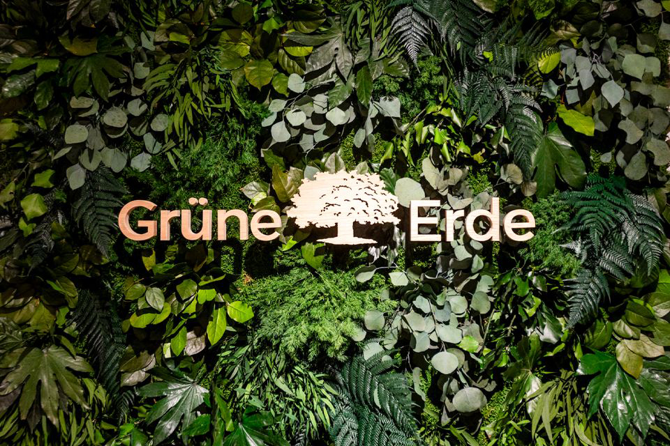 Grüne Pflanzenwand mit Logo und natürlichem Markenauftritt