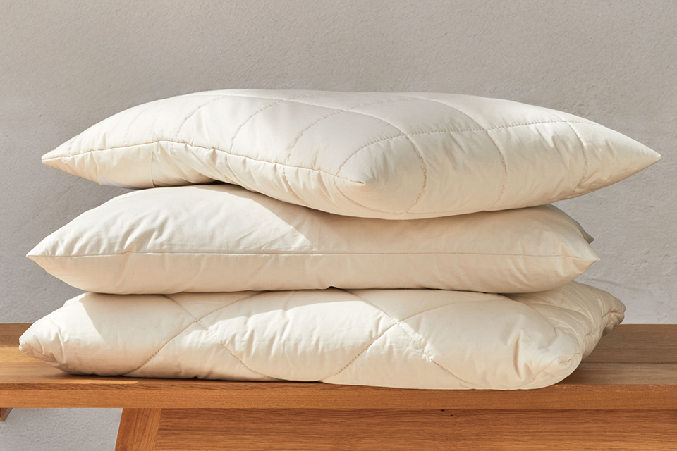 Drei Schlafkissen sind auf einer dekorativen Holzbank gestapelt