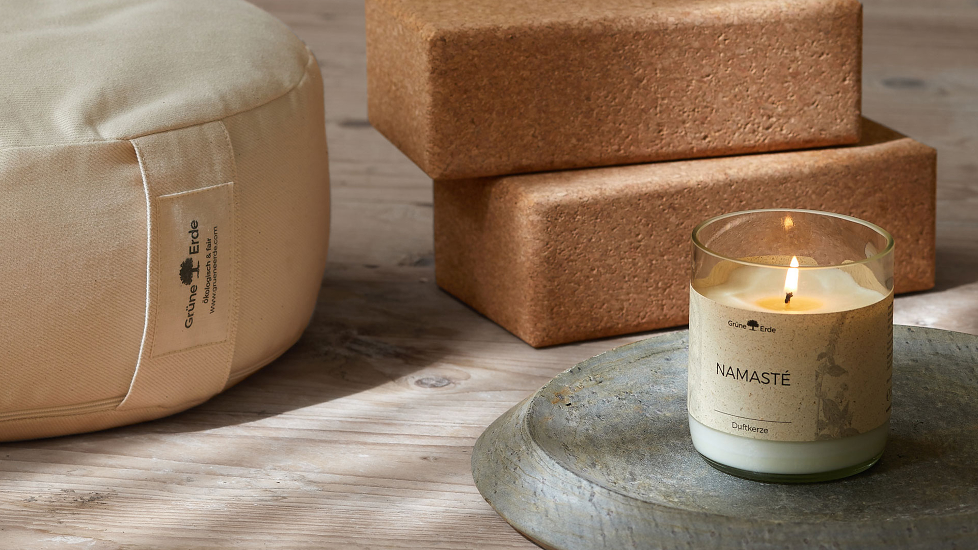 Duftkerze Namaste auf einer Steinplatte neben zwei Jogablöcke