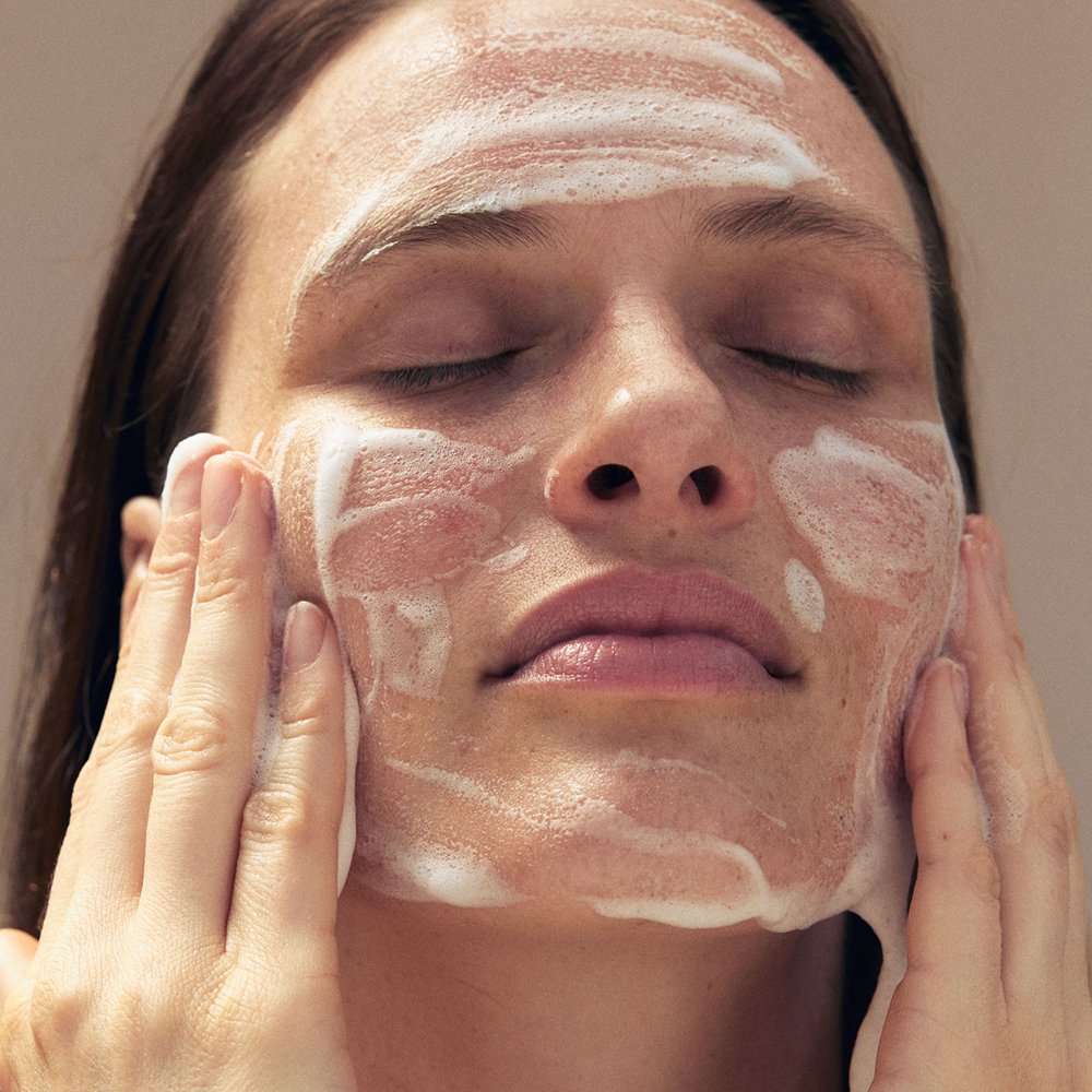 Frau reinigt Gesicht mit Waschschaum