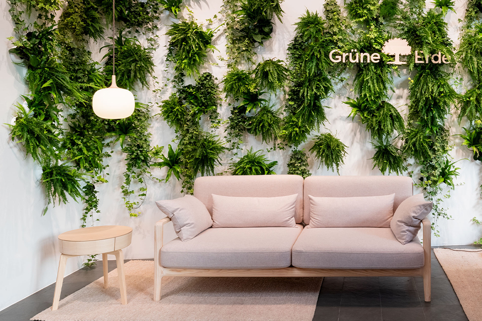 Helles Sofa vor grüner Pflanzenwand im modernen Raum