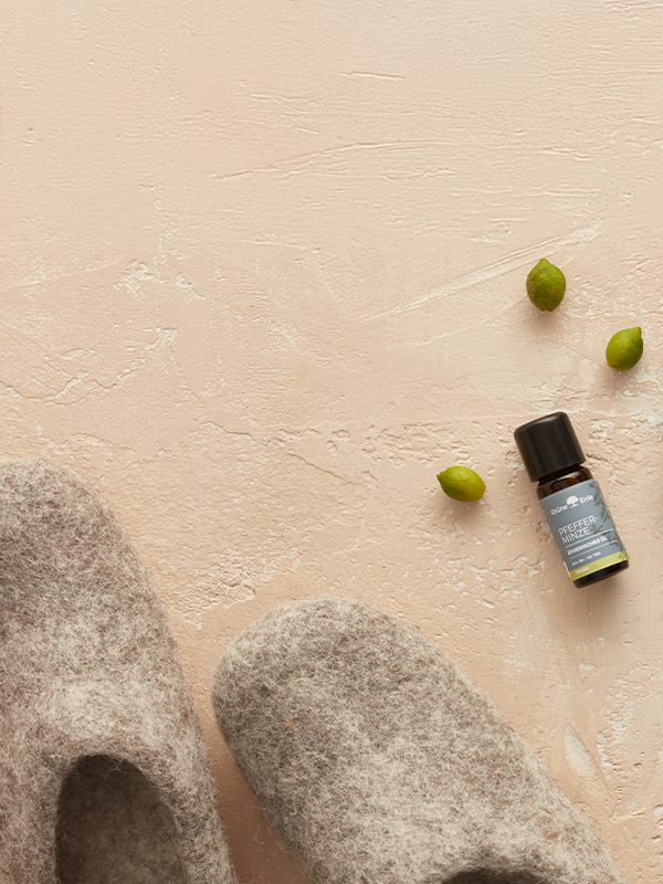 Basisöl und ätherische Öle mit Knospen und einer Zitrone dekorativ angeordnet