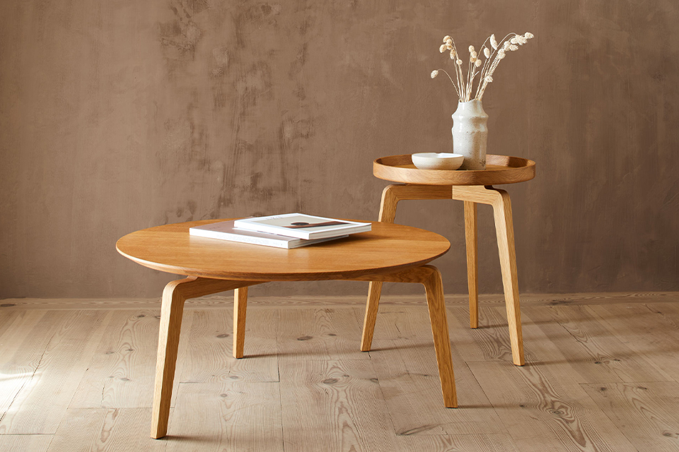 Zwei kleine Holztische stehen nebeneinander in einem Raum