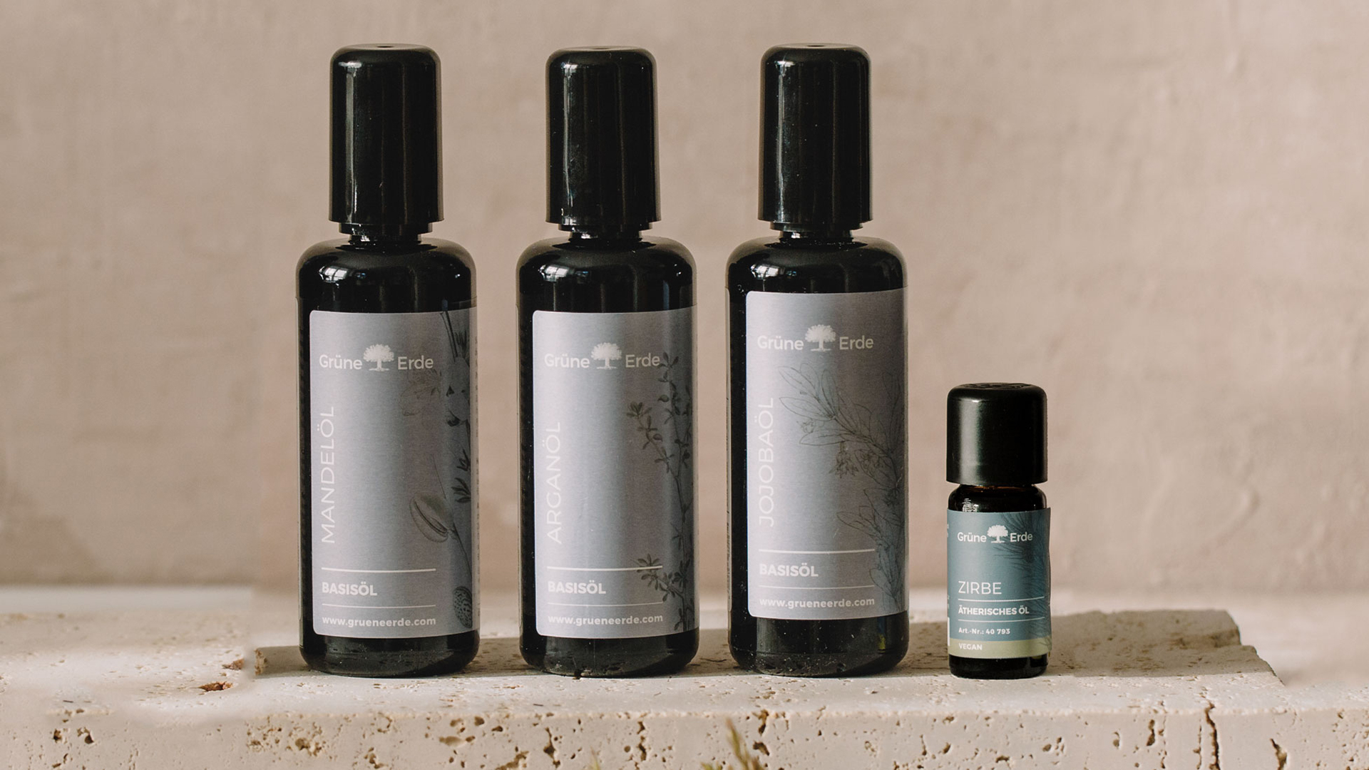 Drei Basisöle und ein Aromaöl auf einer Steinplatte