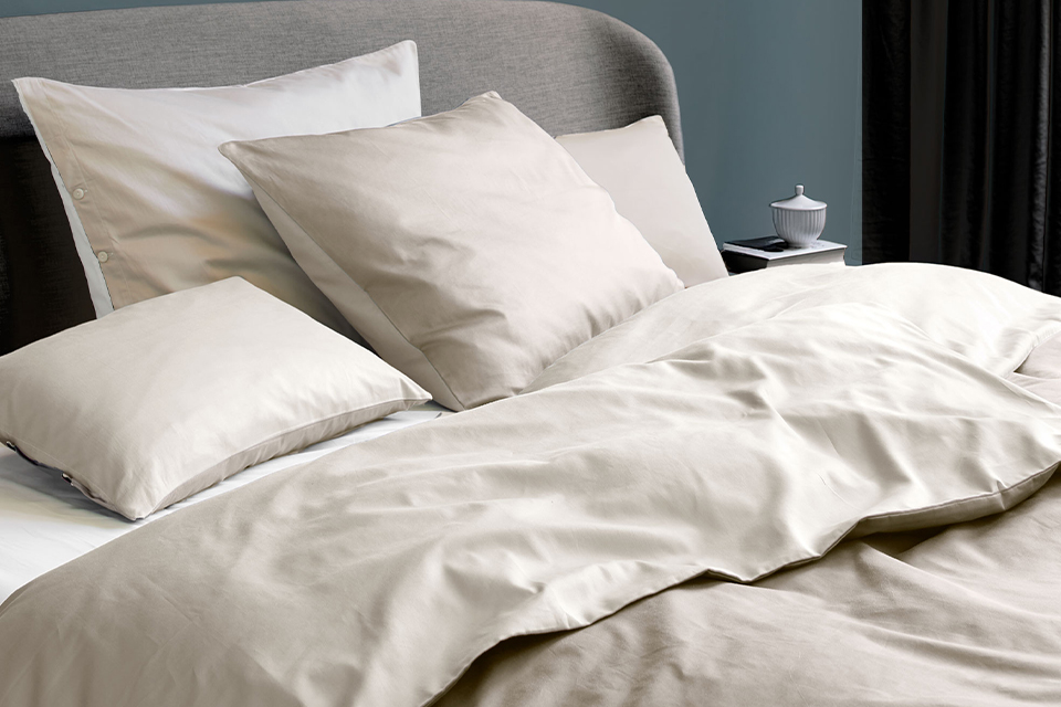 Grauweiße Bettwäsche auf einem Bett in einem Schlafzimmer