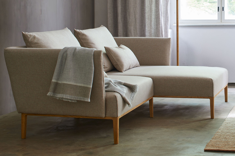 Beiges Sofa mit einer Wohndecke über der Lehne in einem Wohnzimmer