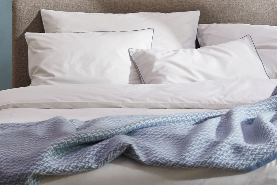 Bettwäsche Edna in blau weiß und Wohndecke Nolan in blau auf einem Bett