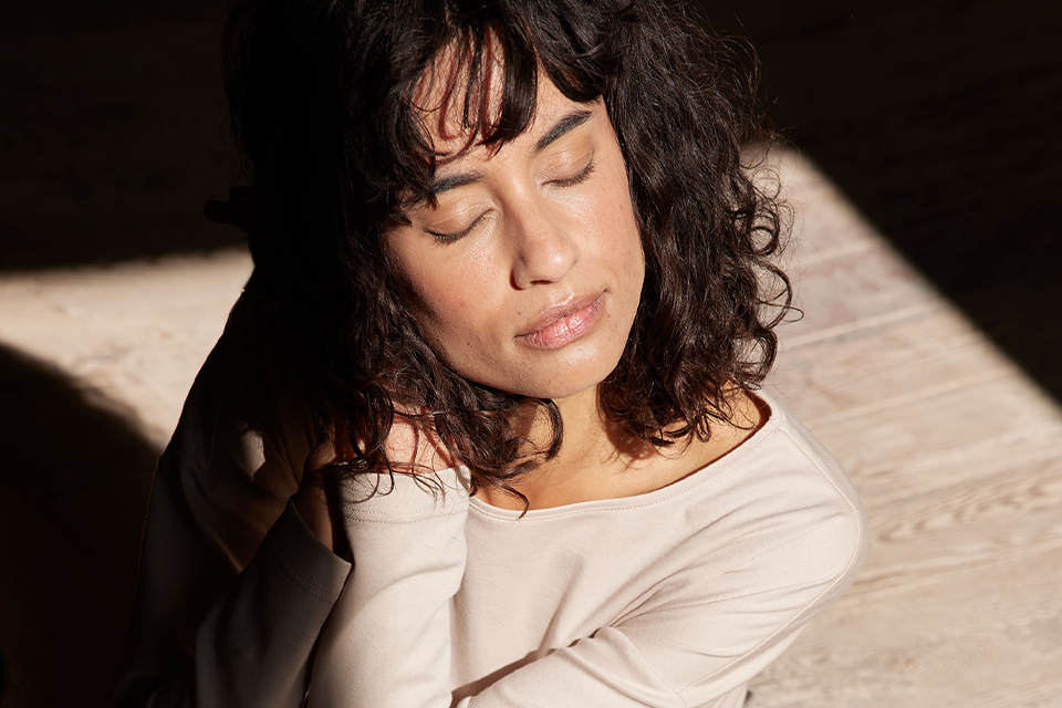 Frau mit lockigem Haar ruht entspannt im sanften Licht