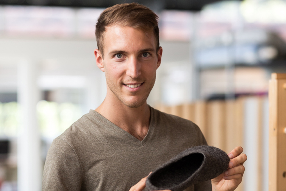 Lächelnder Mann hält Hausschuh aus Filz in den Händen