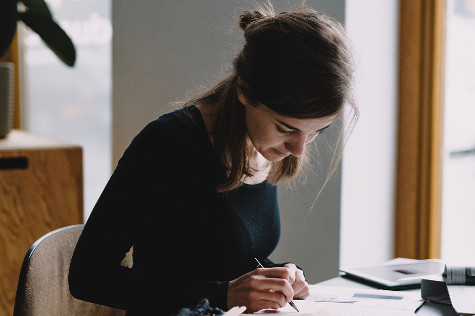 Produktdesignerin skizziert etwas auf einem Buch