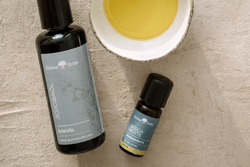 Ein Basisöl und ein Aromaöl liegen neben einer mit Öl gefüllten Schale