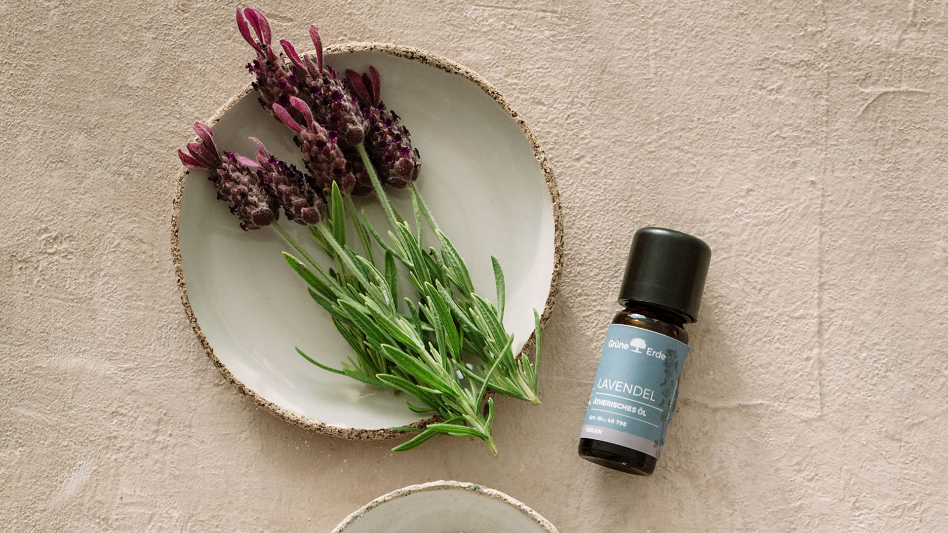 Aromaöl neben einer Keramikschale mit dekorativen Blumen