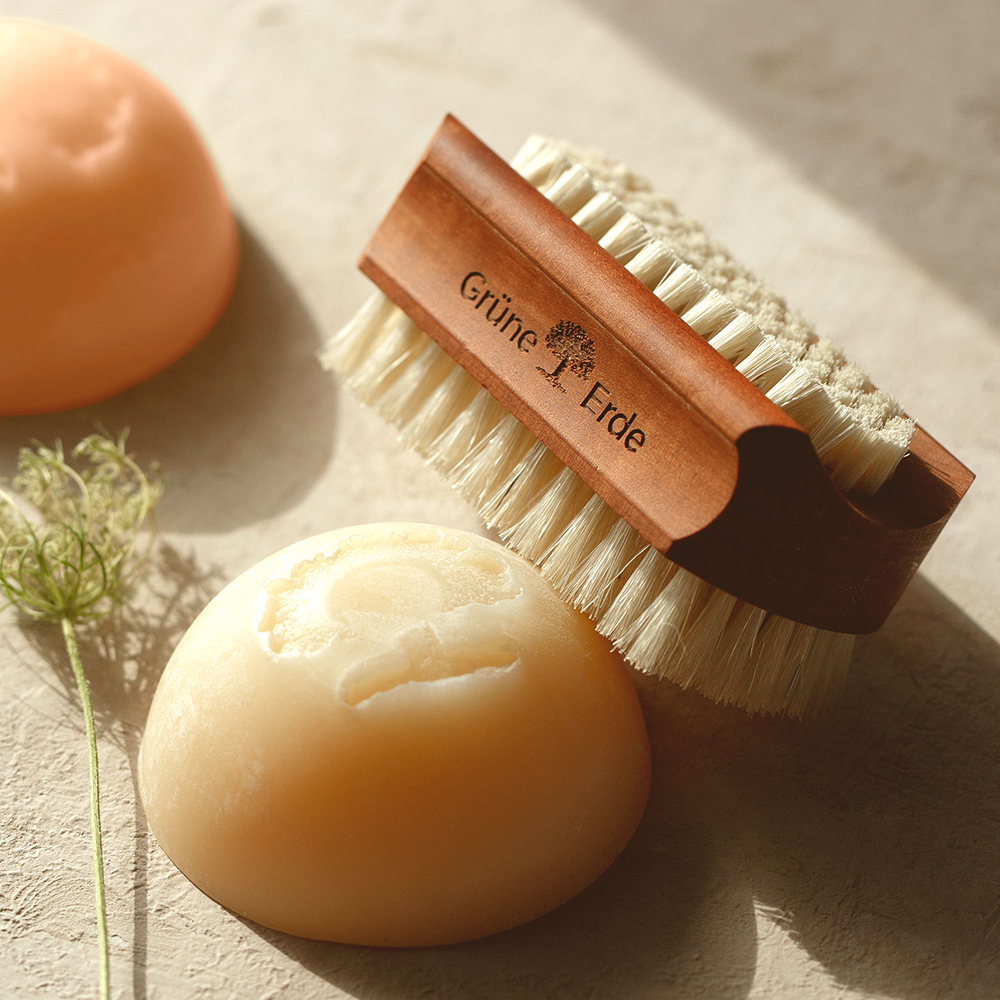 Zwei feste Seifen und ein Bürstchen mit einem dekorativen Blümchen