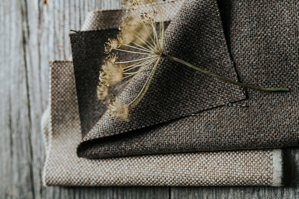 Gefaltete Möbelstoffe in Naturtönen auf einer Holzoberfläche