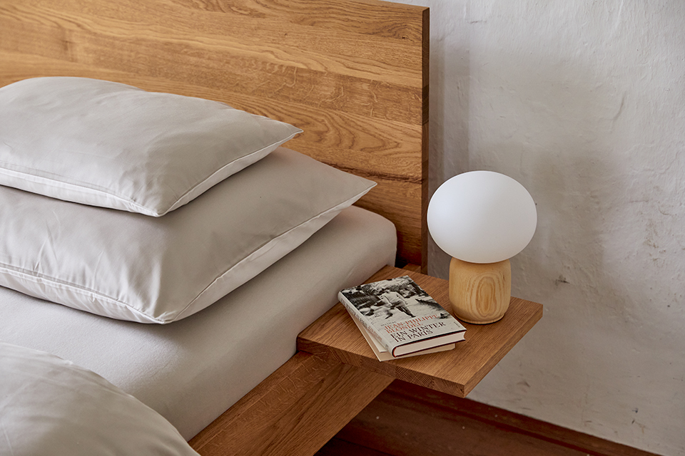 Nachttisch mit Lampe einem Buch und gepolstertem Bett