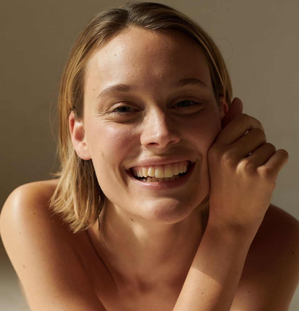 Frau hat rechte Hand an der Wange und lächelt