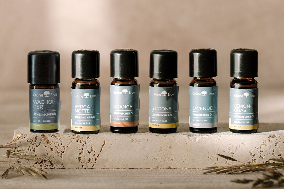 Sechs verschiedenfarbige Aromaöle nebeneinander auf einem Stein