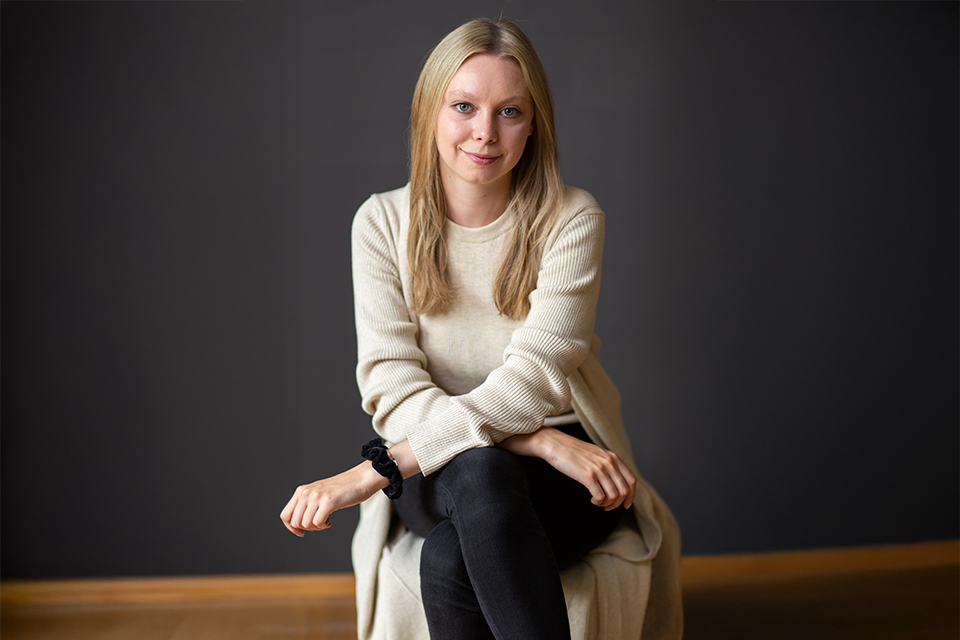 Blonde Frau sitzt ruhig vor dunklem Hintergrund mit sanftem Licht