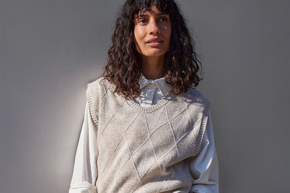 Frau trägt hellen Pullover vor neutralem Hintergrund